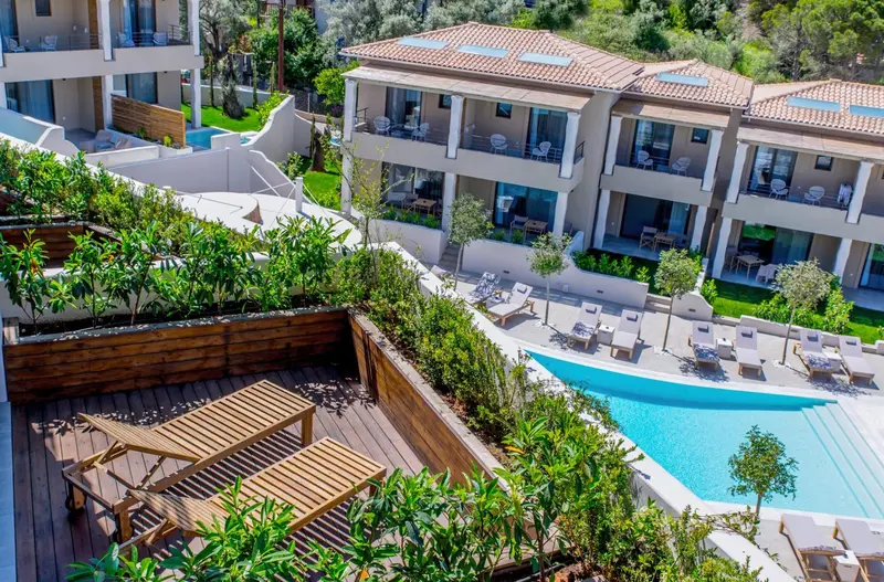 Vue aérienne d'une piscine entourée de transats et de végétation luxuriante.