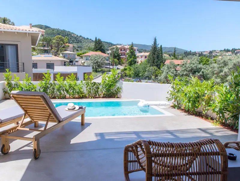 Transats et petite piscine sur une terrasse ensoleillée avec vue sur la végétation.