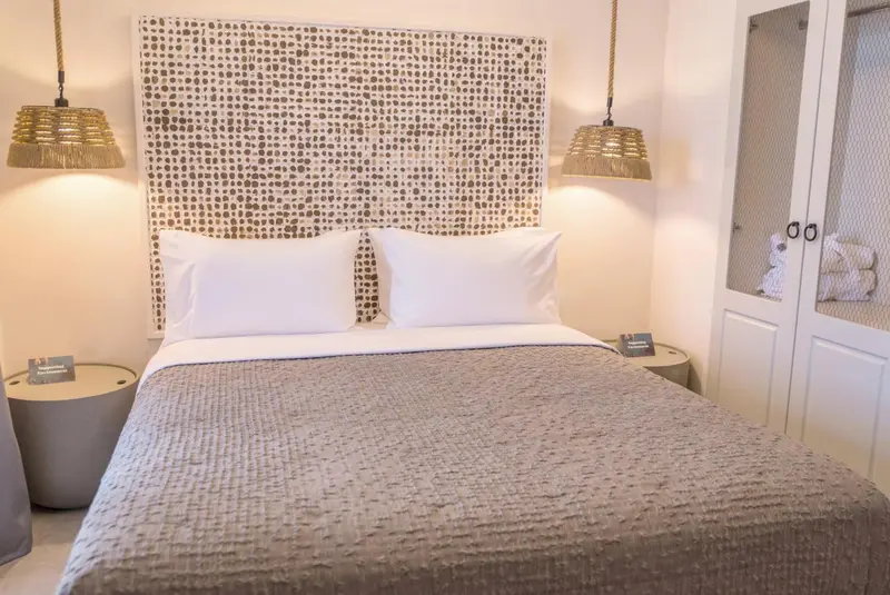 Une chambre lumineuse avec un grand lit recouvert d'une couverture texturée.