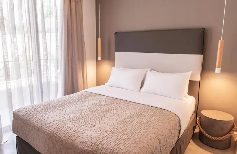 Une chambre avec un grand lit recouvert d'une courtepointe et de coussins blancs.