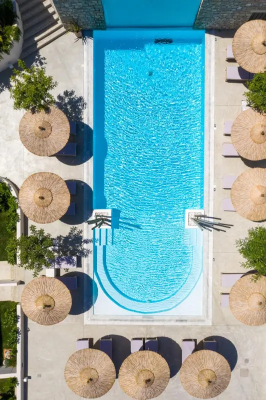 Vue aérienne d'une piscine rectangulaire entourée de parasols et de chaises longues.