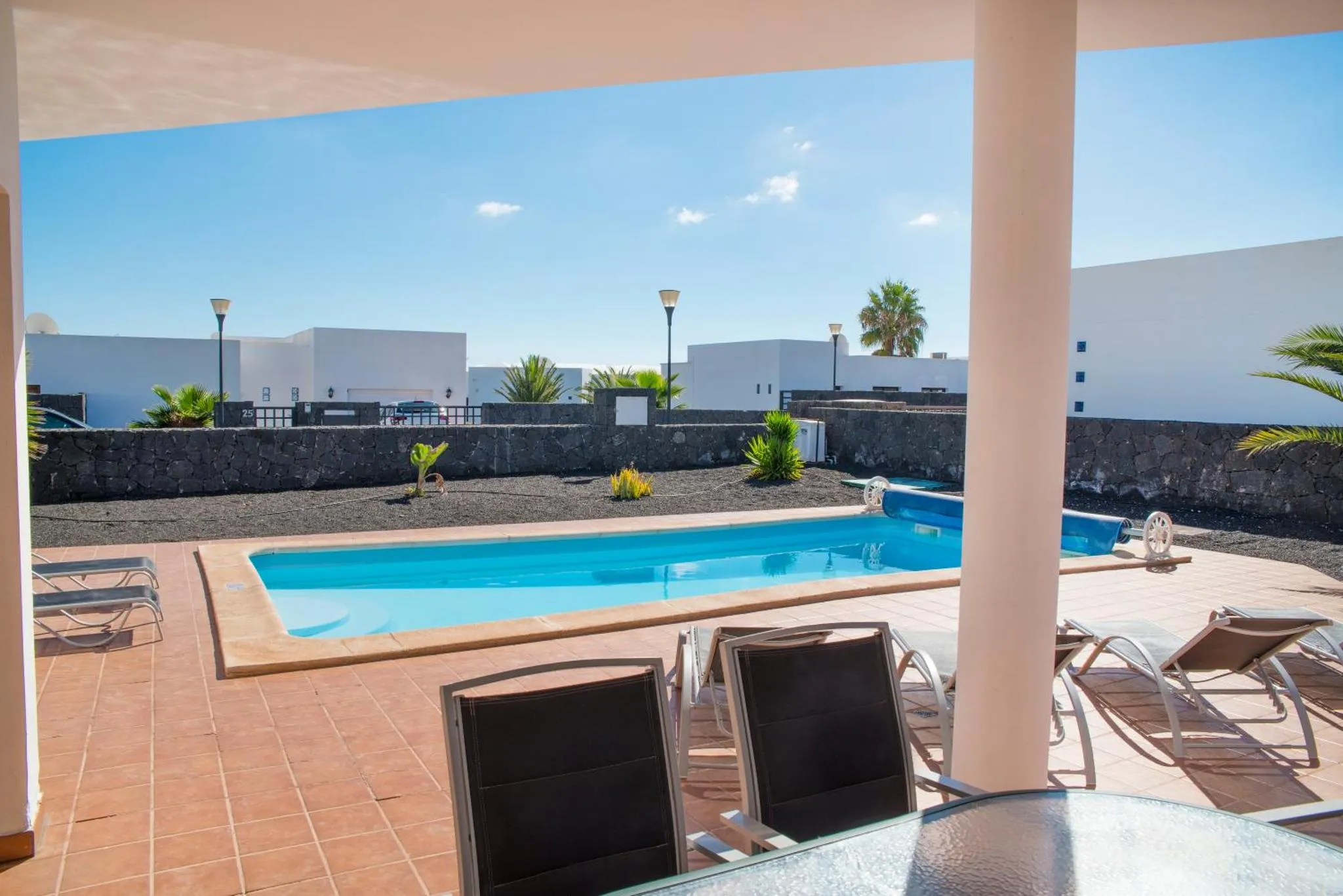 Une piscine rectangulaire avec des transats et des plantes tropicales.