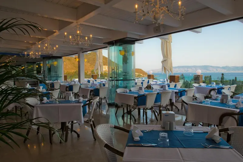 Une salle lumineuse avec des tables dressées face à une vue sur la mer.