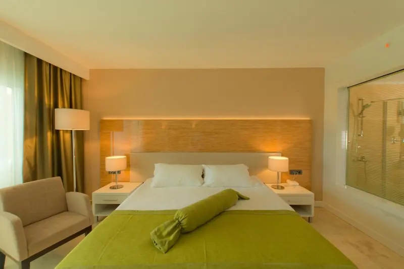 Une chambre lumineuse avec un grand lit et un fauteuil.