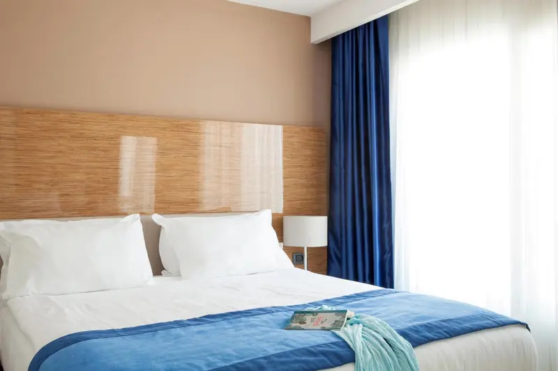 Lit double avec oreillers blancs et couverture bleue dans une chambre lumineuse.