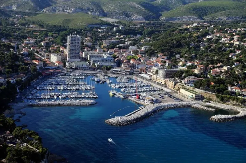 Vue aérienne d'une ville côtière avec un port de plaisance et des bâtiments.
