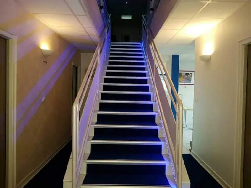 Un escalier moderne avec des lumières bleues intégrées aux marches.