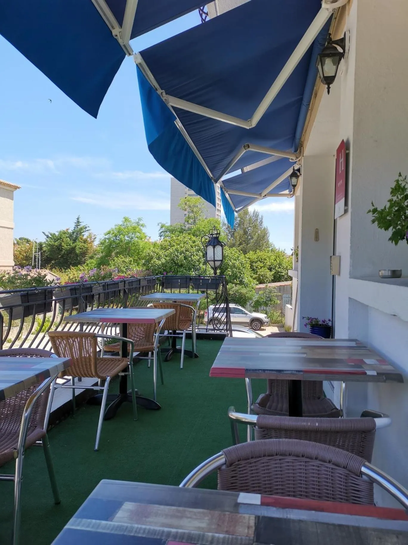 Terrasse ombragée avec tables et chaises en osier.
