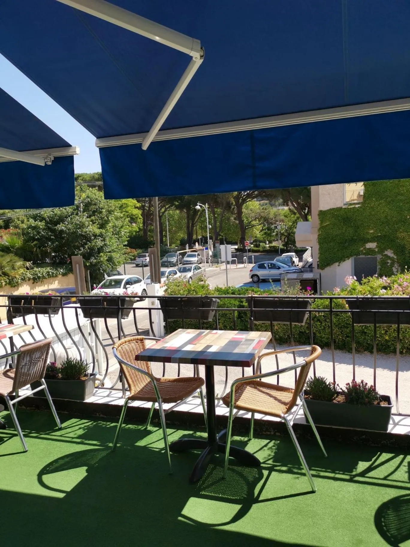 Terrasse ombragée avec tables et chaises en osier.
