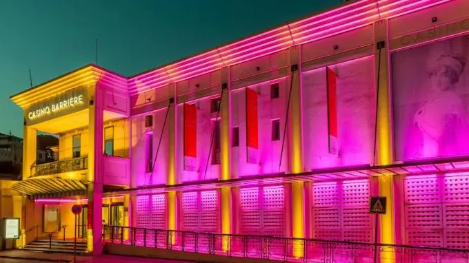 Façade d'un bâtiment illuminé de couleurs vives avec une enseigne lumineuse.