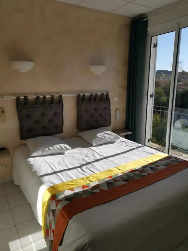 Une chambre lumineuse avec un lit double et un accès à une terrasse.