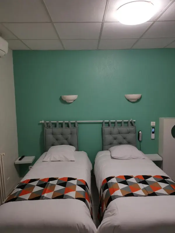 Deux lits simples dans une chambre aux murs verts.