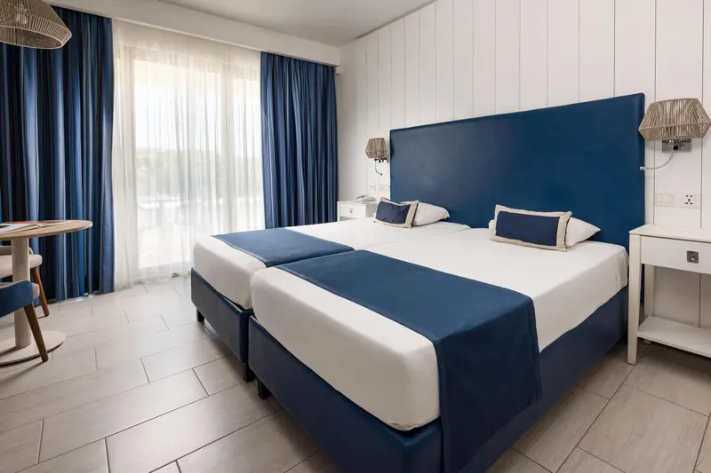 Une chambre lumineuse avec deux lits simples et un coin repas.