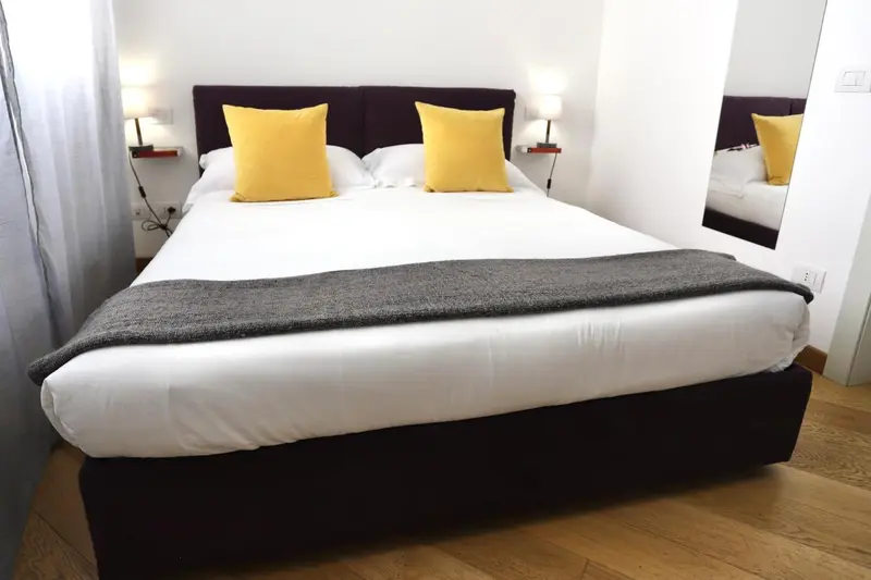 Une chambre lumineuse avec un grand lit recouvert d'une courtepointe et de coussins.