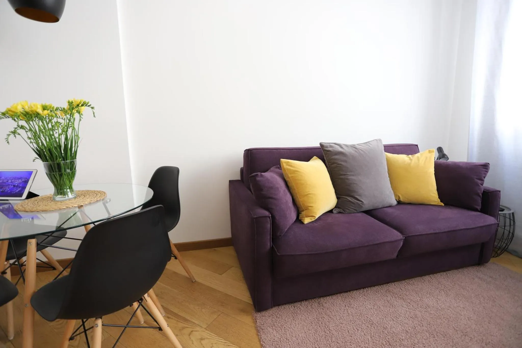 Un canapé violet et des chaises noires sont disposés autour d'une table en verre.