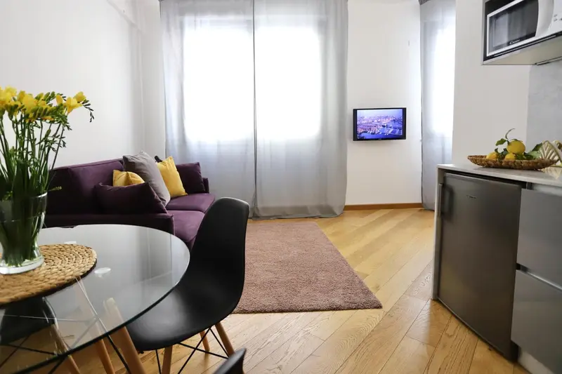 Un salon lumineux avec un coin repas et une kitchenette.