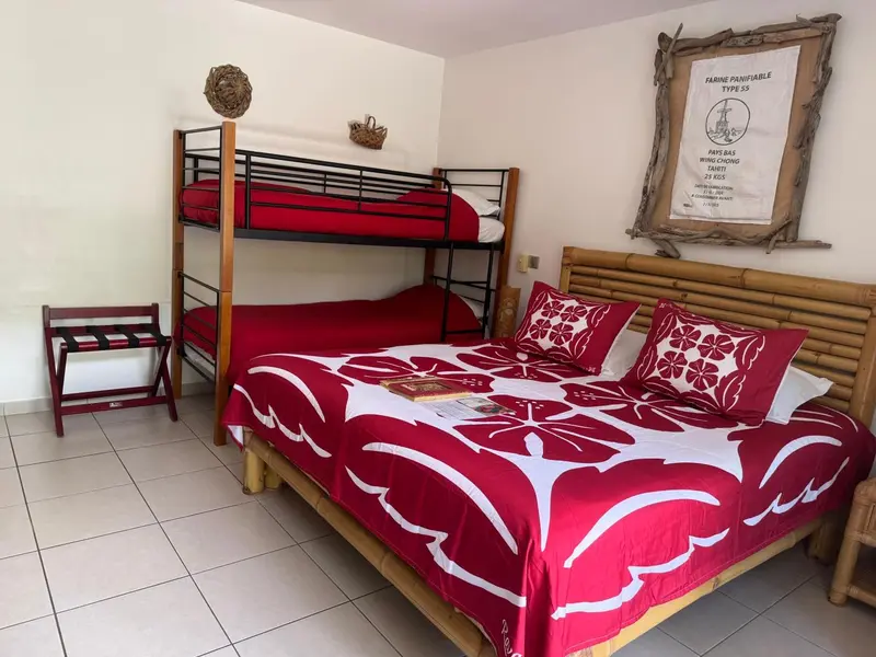 Chambre avec lits superposés et grand lit recouvert d'une courtepointe à motifs floraux.