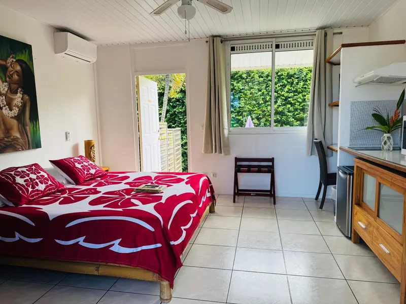Une chambre lumineuse avec un lit recouvert d'un couvre-lit fleuri et une kitchenette.