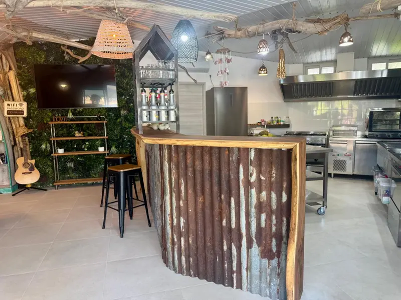 Un comptoir de bar en métal ondulé dans une cuisine professionnelle lumineuse.