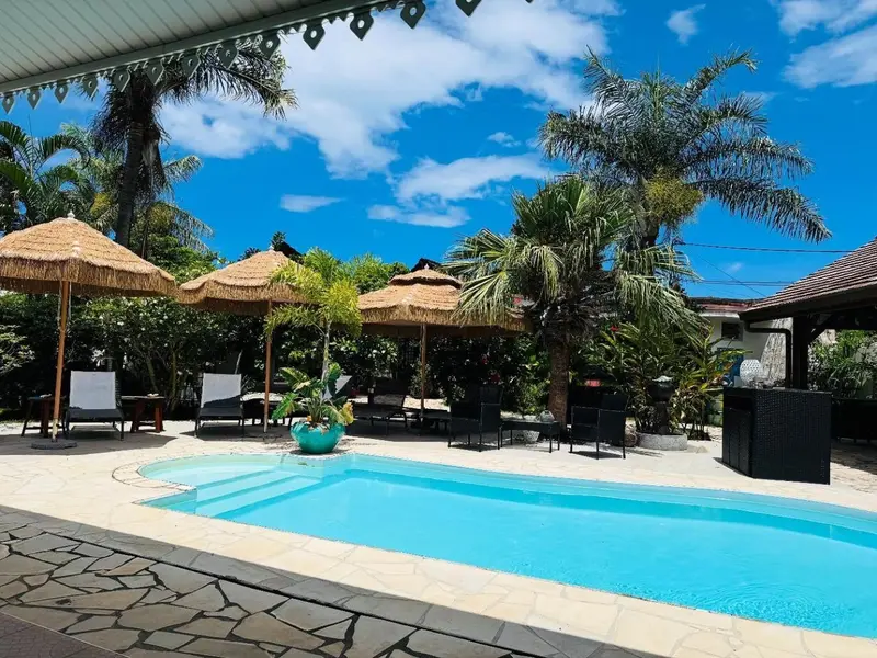 Terrasse avec piscine et mobilier de jardin sous des toits de chaume.