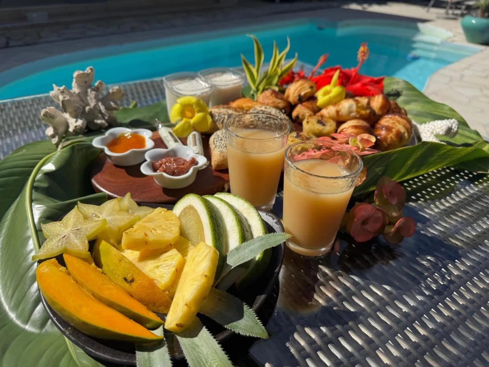 Présentation de plats exotiques et de boissons fraîches sur une table près d'une piscine.