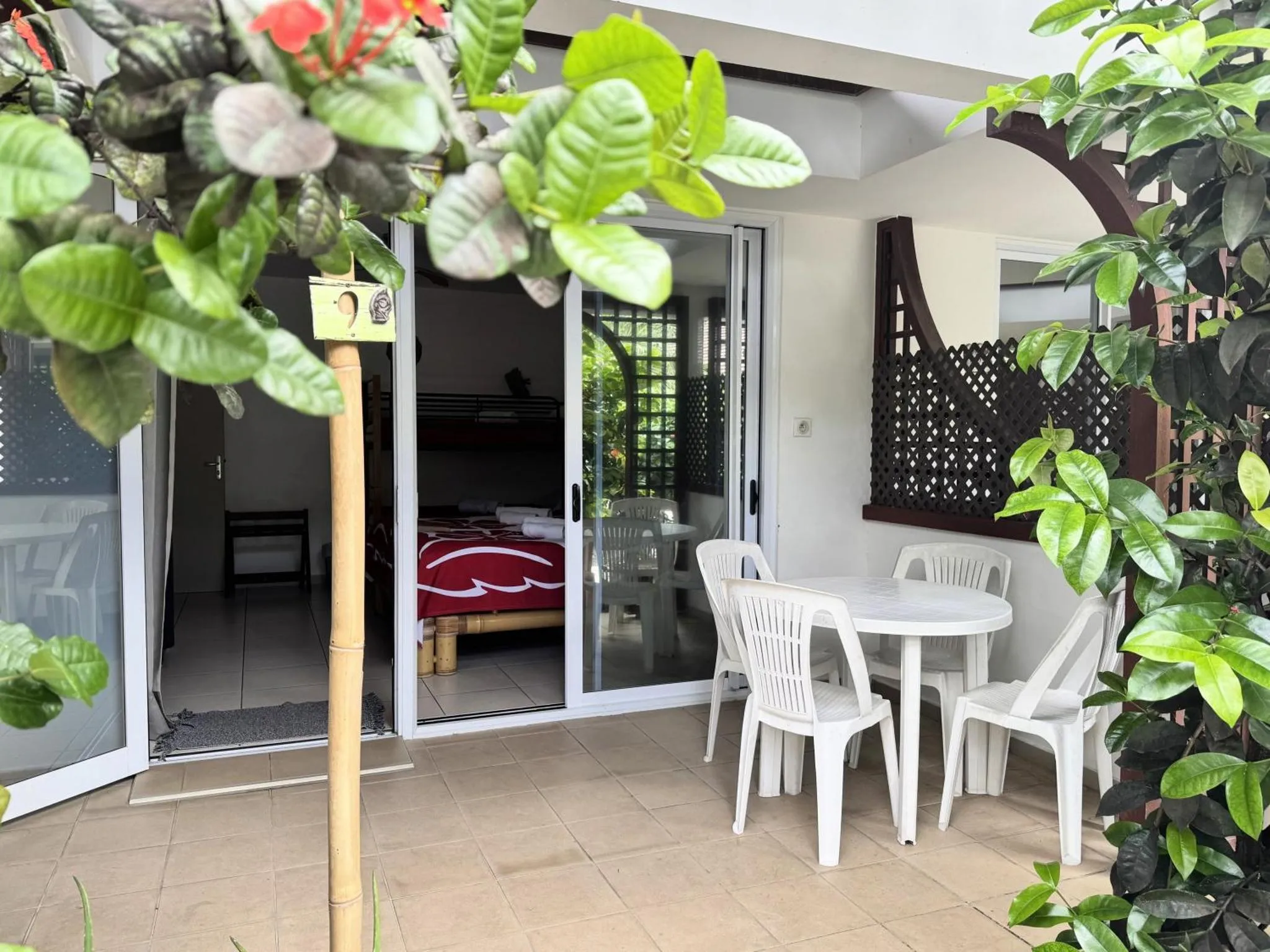 Une terrasse ombragée donne sur une chambre avec un lit et un coin repas.
