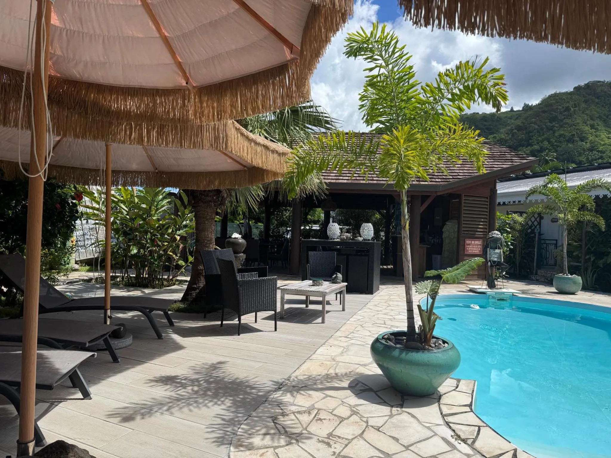 Espace de détente extérieur avec parasols et piscine.