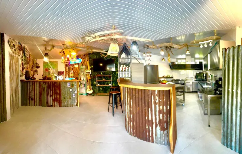 Un bar avec un comptoir incurvé et une cuisine professionnelle en fond.