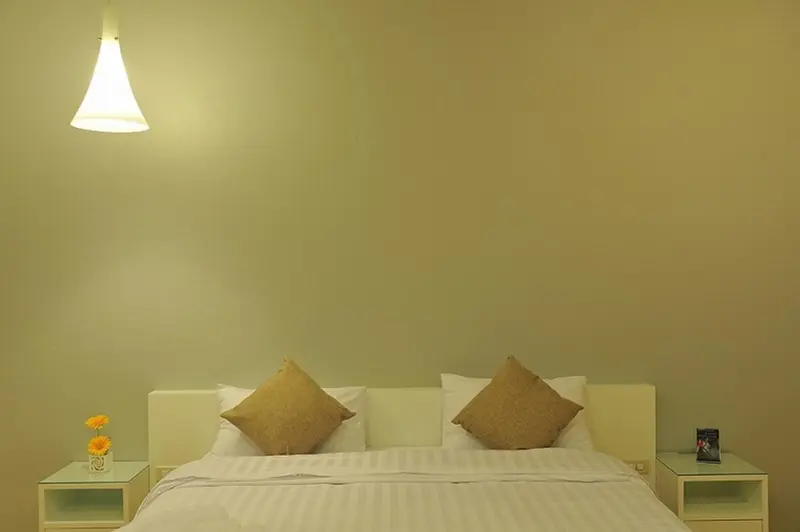 Une chambre lumineuse avec un grand lit et des oreillers décoratifs.
