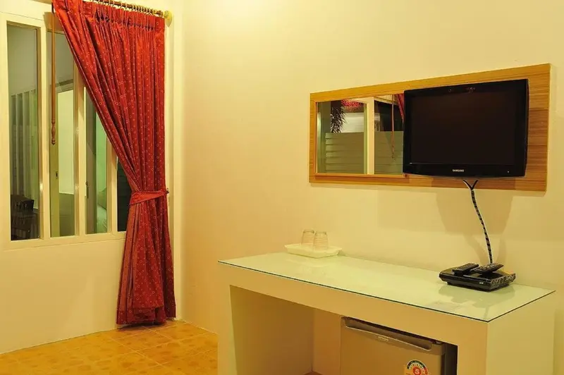 Une chambre lumineuse avec un téléviseur mural et un petit bureau.