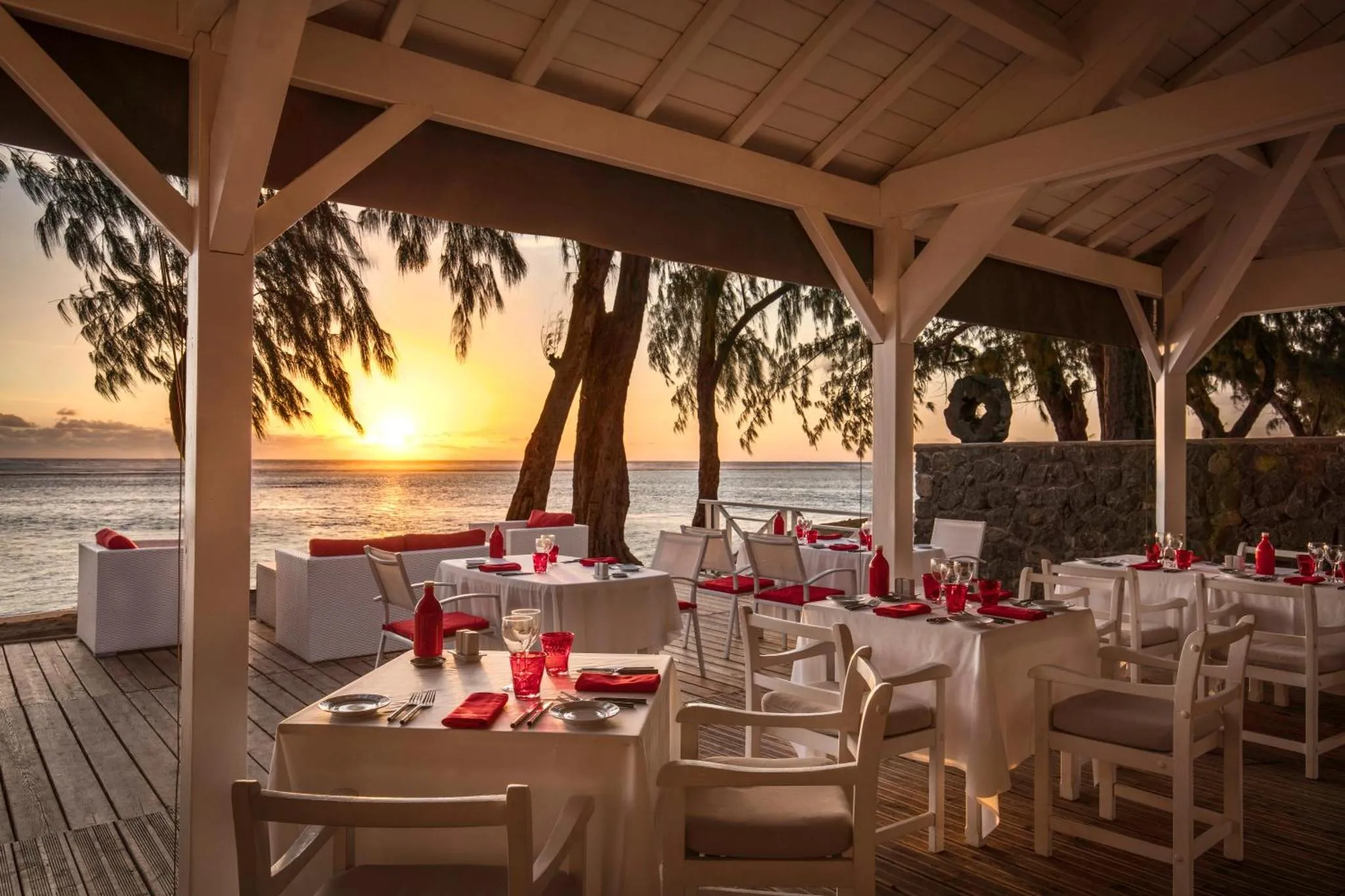 Tables dressées en terrasse face à la mer au coucher du soleil.