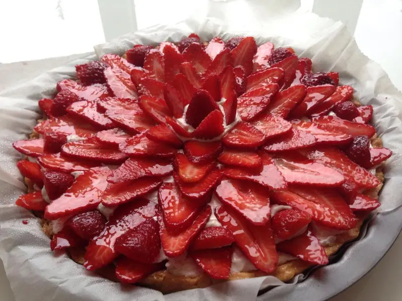 Une tarte aux fraises décorée avec des fraises fraîches et une crème pâtissière.