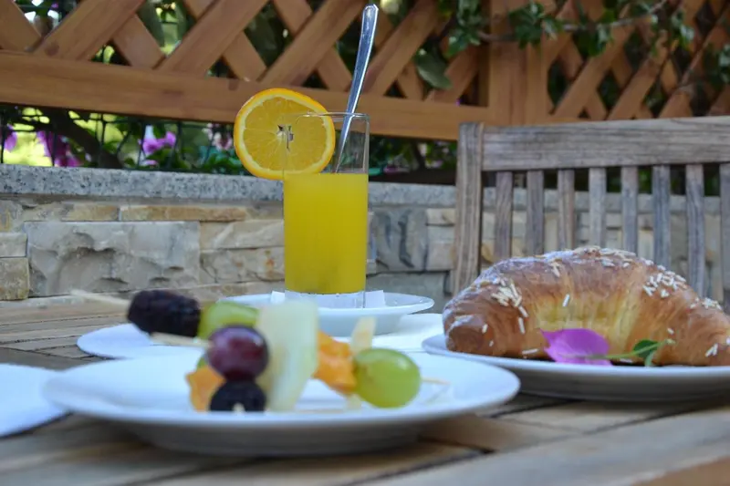 Une table est dressée avec des fruits frais, un croissant et un jus d'orange.