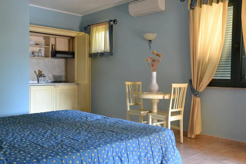Une petite cuisine et une table à manger se trouvent dans une chambre lumineuse.