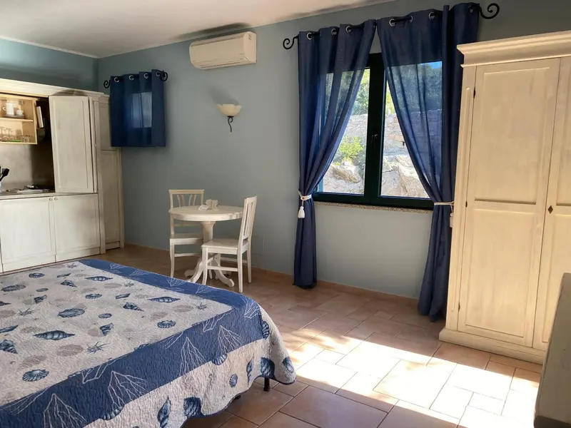 Une chambre lumineuse avec un lit recouvert d'une courtepointe à motifs et un coin repas.