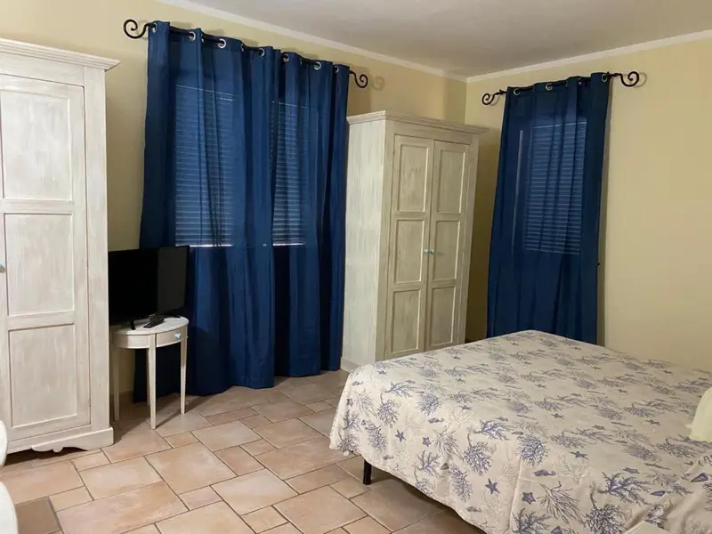 Une chambre lumineuse avec un lit recouvert d'une courtepointe et des armoires.