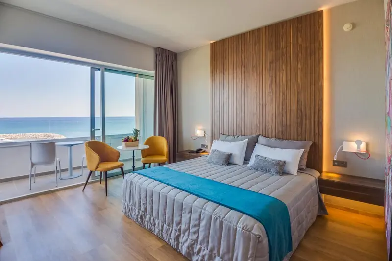 Chambre lumineuse avec un grand lit et une vue sur la mer.