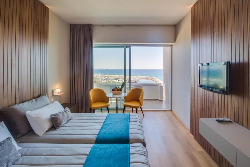 Une chambre lumineuse avec un lit fait et une vue sur la mer.