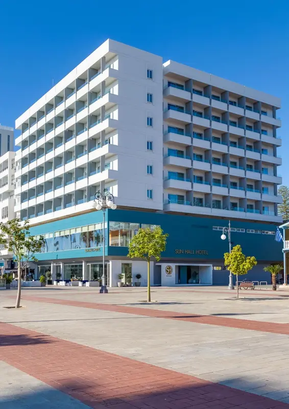 Bâtiment moderne à plusieurs étages avec des balcons et une façade blanche et turquoise.