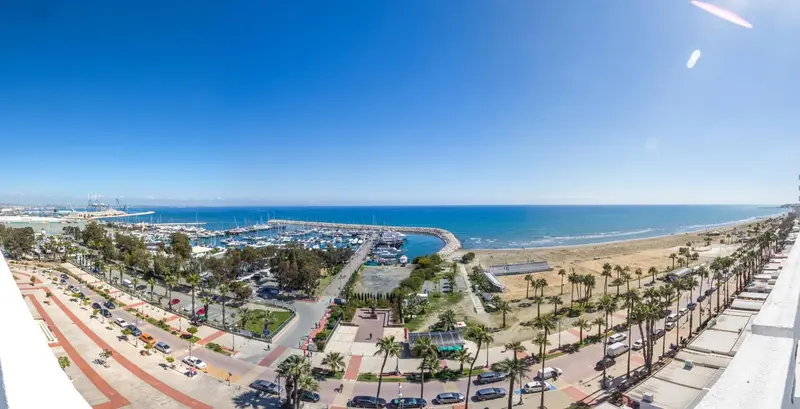 Vue panoramique sur une marina et une plage ensoleillées.
