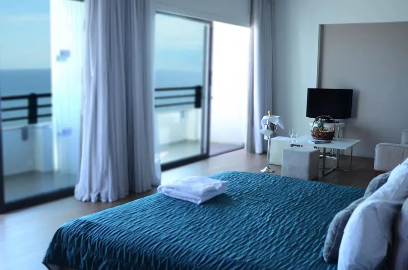 Chambre avec un grand lit et une vue sur la mer à travers de larges baies vitrées.