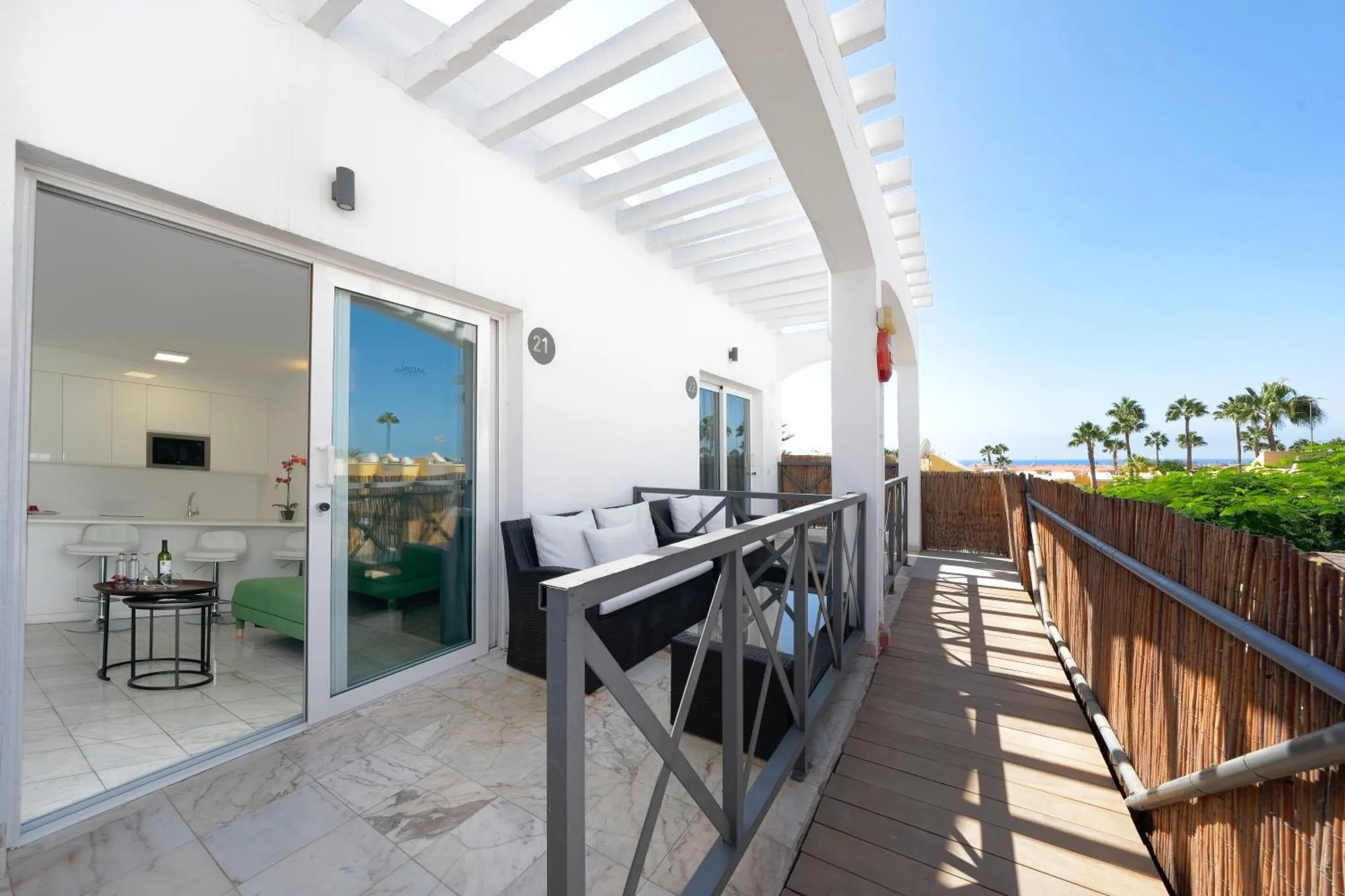 Terrasse carrelée avec mobilier d'extérieur et vue sur la mer.