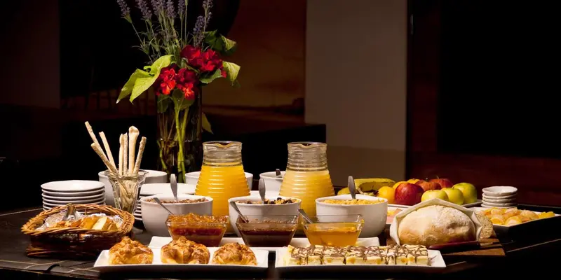 Une table garnie de viennoiseries, de fruits et de boissons.