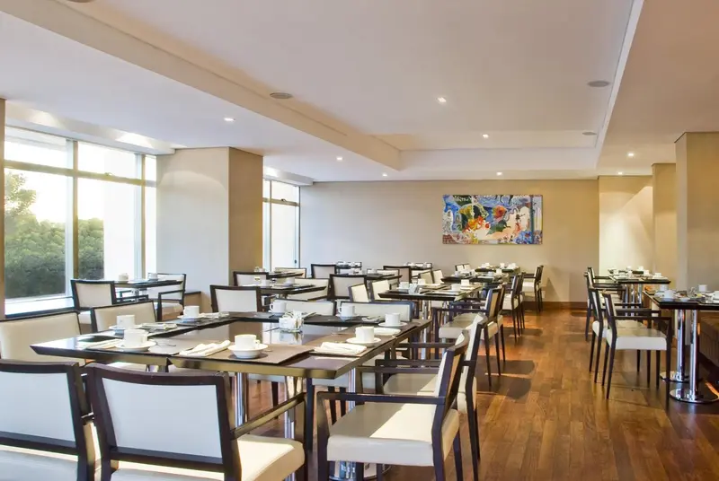 Une salle lumineuse avec des tables dressées pour un repas.