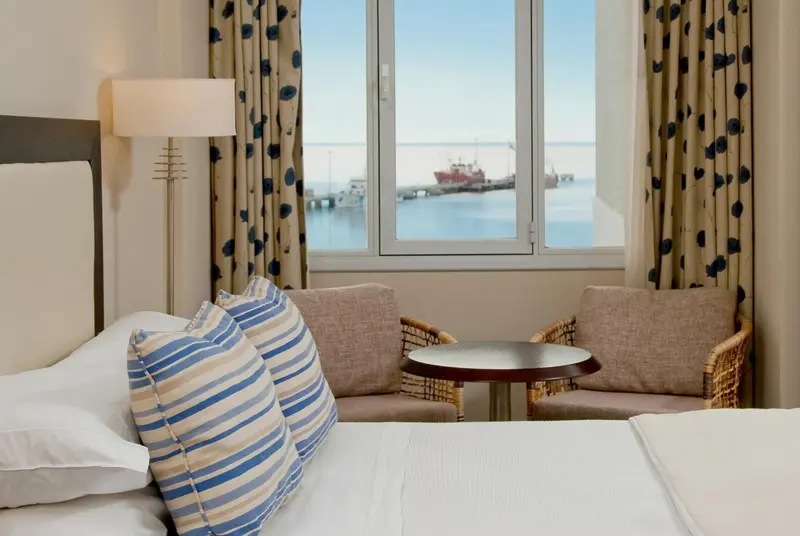 Une chambre lumineuse avec vue sur un port.