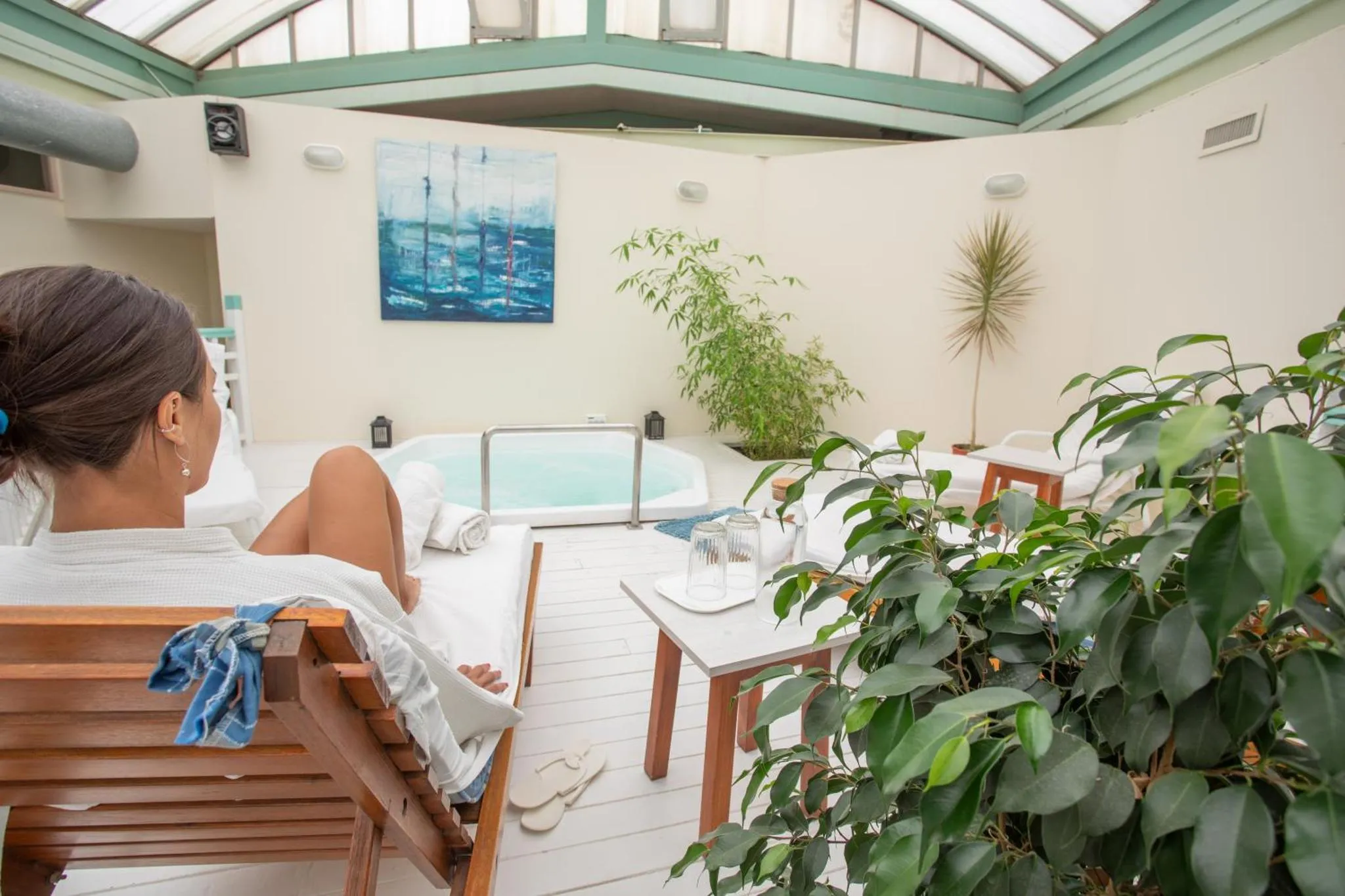 Une femme se détend sur une chaise longue près d'un jacuzzi intérieur.