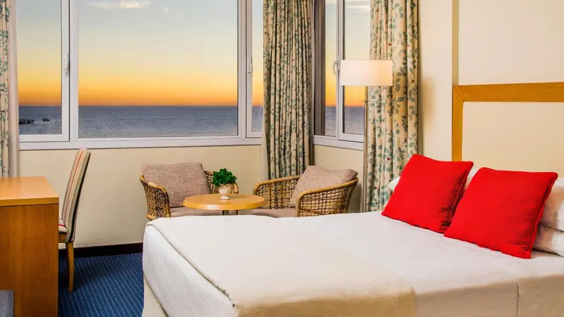 Une chambre lumineuse avec vue sur la mer au coucher du soleil.