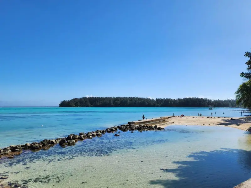 Une plage de sable blanc s'avance dans une eau turquoise claire.