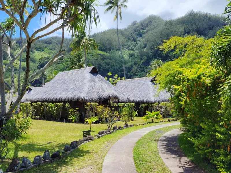 Des bungalows traditionnels avec toits de chaume se dressent au milieu d'une végétation luxuriante.