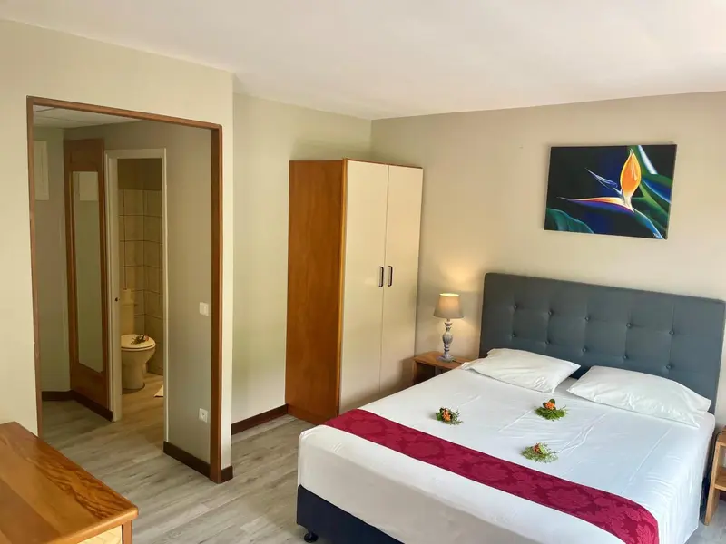 Une chambre lumineuse avec un grand lit et un accès à une salle de bain.